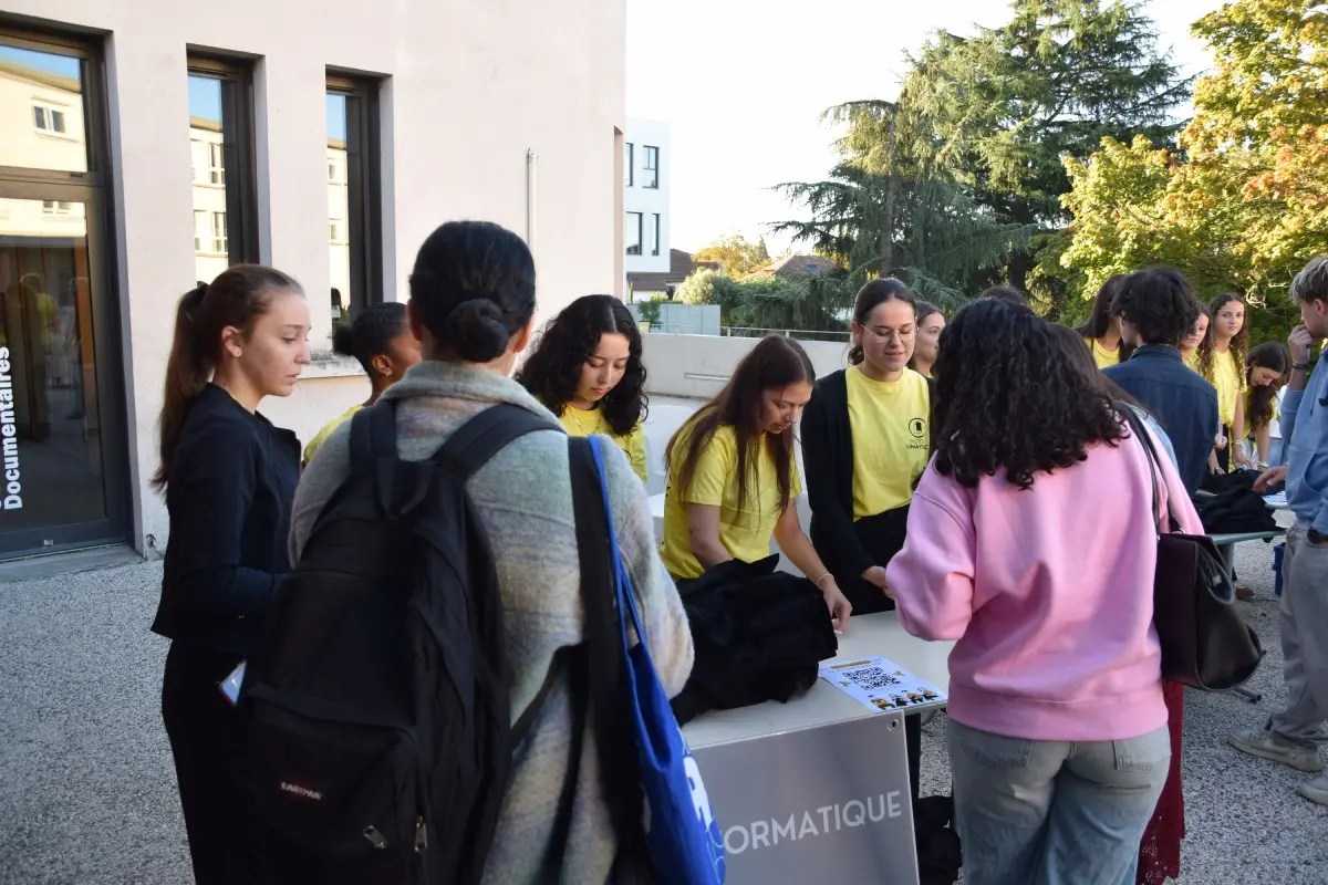 Étudiants se rassemblent autour d'un stand d'accueil extérieur pour préparer la rentrée à l'Institut Limayrac auprès de bénévoles en t-shirts jaunes.