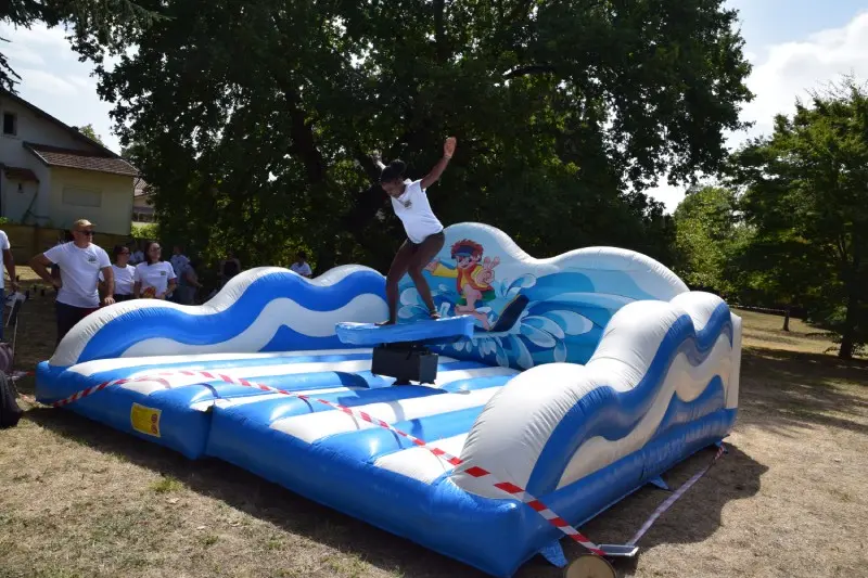 Une étudiante en équilibre sur un simulateur de surf mécanique gonflable lors de la Journée d'Intégration à Toulouse organisée par l'Institut Limayrac.