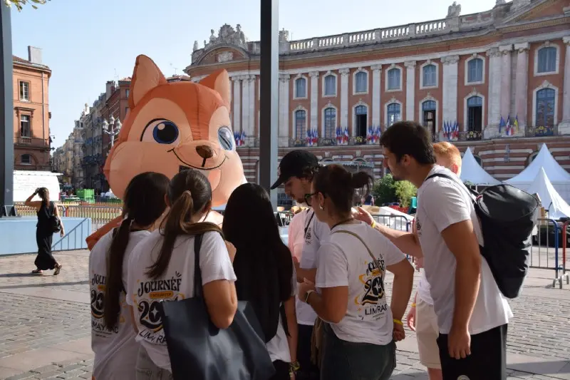 Groupe d'étudiants de l'Institut Limayrac autour d'une mascotte gonflable sur la place du Capitole lors de la journée d'intégration à Toulouse.