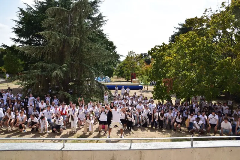 Grande foule d'étudiants en t-shirts blancs faisant la ola dans le parc du campus lors de la Journée d'Intégration à Toulouse de l'Institut Limayrac.